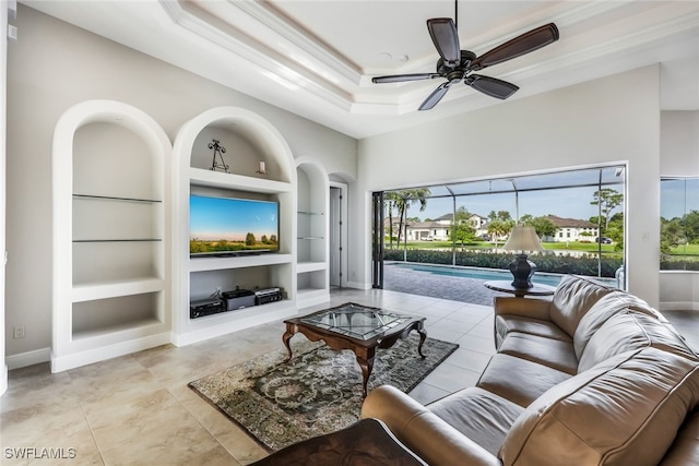 living room featuring a tray ceiling, built in shelves, ceiling fan, and light tile patterned floors