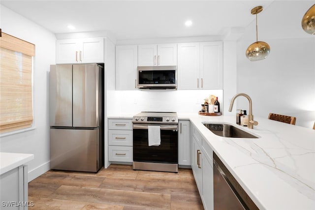 kitchen featuring appliances with stainless steel finishes, hanging light fixtures, white cabinetry, and sink