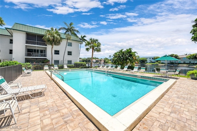 view of swimming pool featuring a patio and a water view