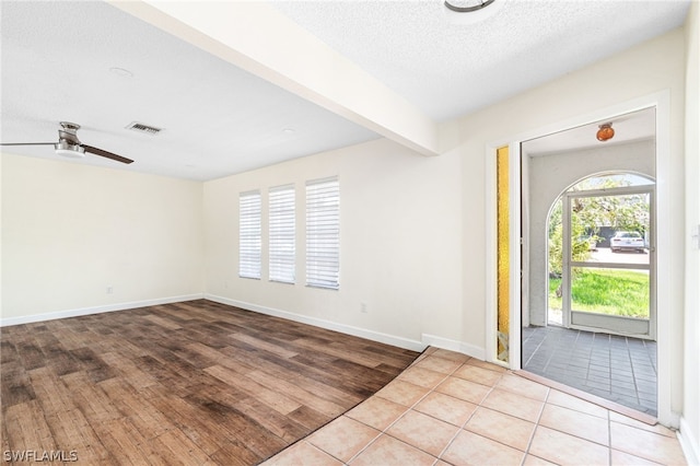 entrance foyer with ceiling fan, beam ceiling, light hardwood / wood-style floors, and a textured ceiling