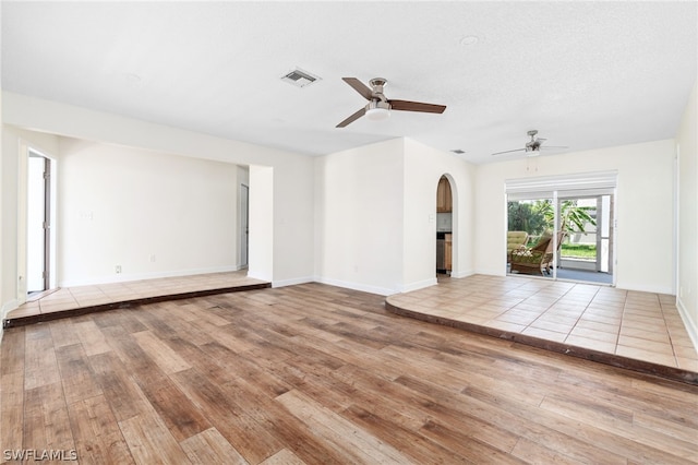 unfurnished living room with hardwood / wood-style flooring, a textured ceiling, and ceiling fan