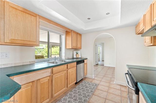 kitchen with sink, light tile patterned floors, appliances with stainless steel finishes, a tray ceiling, and light brown cabinets