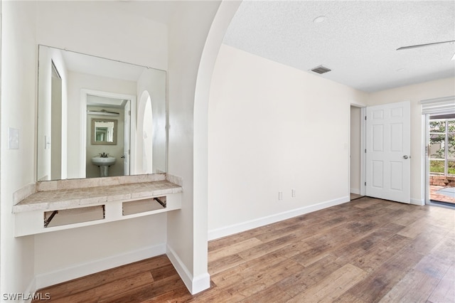 interior space featuring wood-type flooring, sink, and a textured ceiling