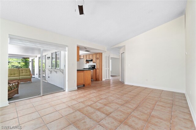 unfurnished living room featuring lofted ceiling, light tile patterned floors, a textured ceiling, and ceiling fan