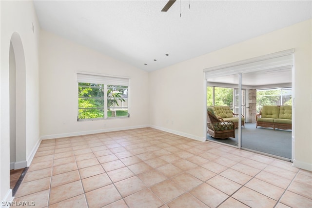 spare room with light tile patterned floors, vaulted ceiling, and ceiling fan