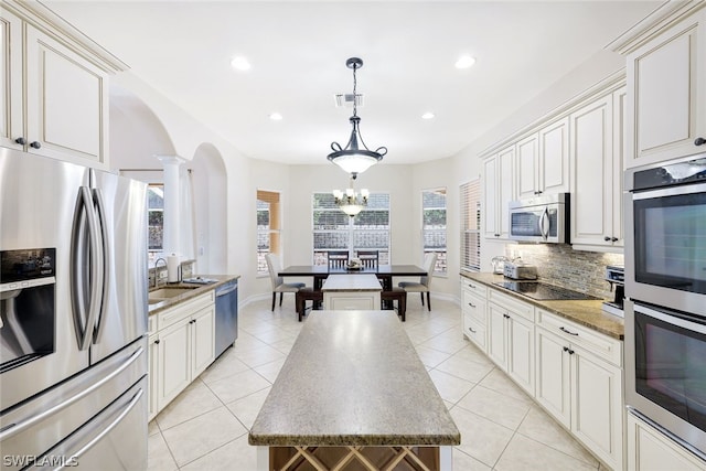 kitchen with light tile patterned flooring, sink, pendant lighting, stainless steel appliances, and backsplash