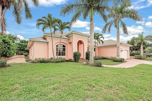 mediterranean / spanish-style house featuring a garage and a front lawn