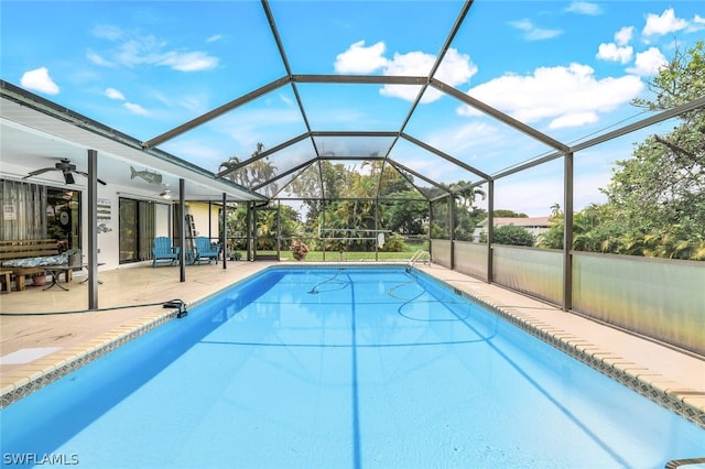 view of swimming pool with glass enclosure, ceiling fan, and a patio