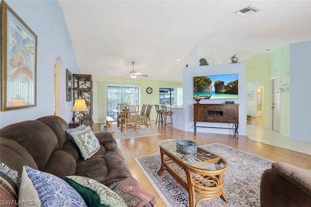 living room with light hardwood / wood-style floors, vaulted ceiling, and ceiling fan