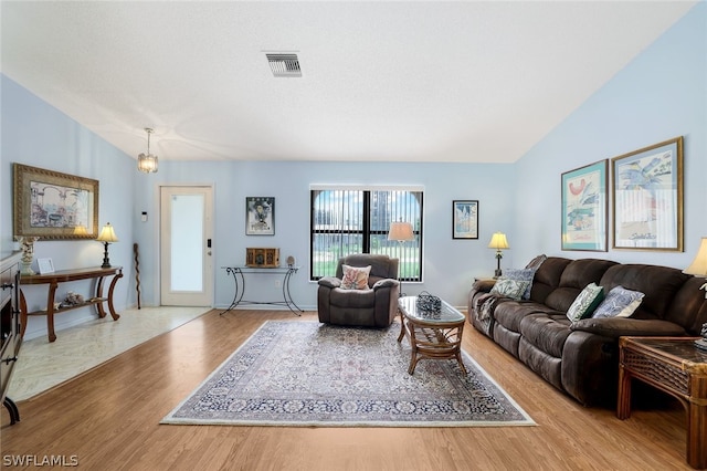 living room with light wood-type flooring, vaulted ceiling, and a chandelier