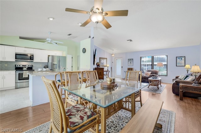 dining area with ceiling fan, light hardwood / wood-style floors, and lofted ceiling