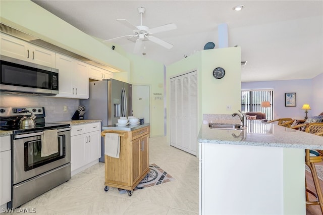 kitchen featuring ceiling fan, backsplash, white cabinetry, sink, and stainless steel appliances