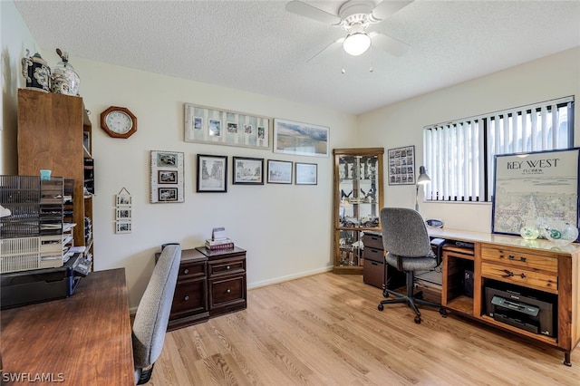 home office featuring light wood-type flooring, ceiling fan, and a textured ceiling