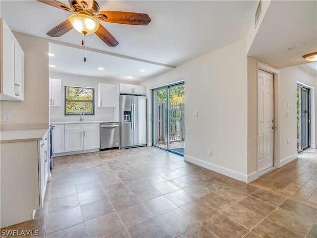 kitchen with appliances with stainless steel finishes, white cabinets, light tile patterned floors, and ceiling fan