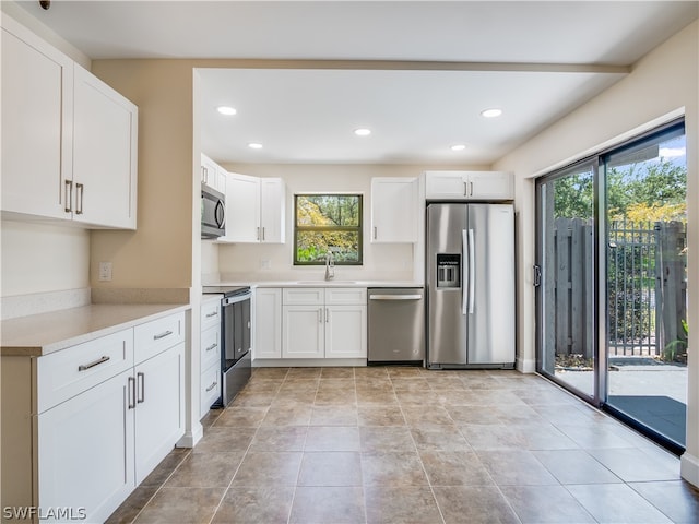 kitchen featuring sink, light tile patterned flooring, white cabinetry, and stainless steel appliances