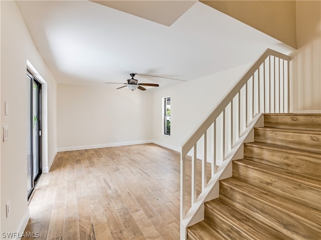 staircase featuring light wood-type flooring and ceiling fan