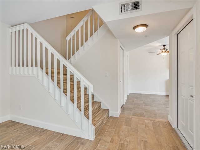 stairs with ceiling fan and light wood-type flooring