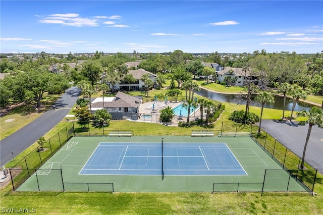 view of tennis court featuring a water view and a fenced in pool