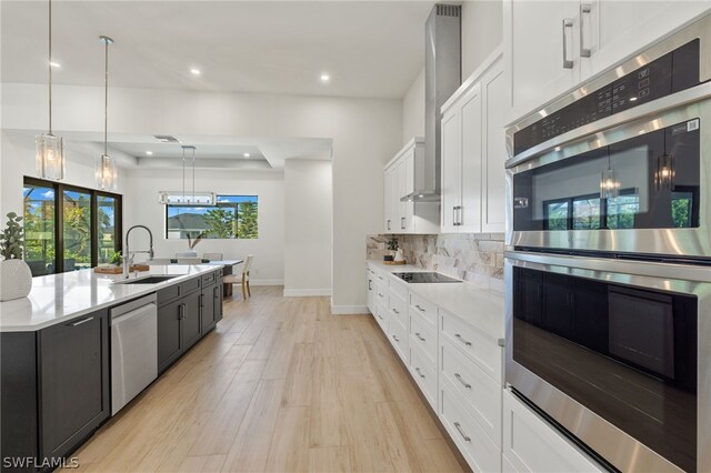 kitchen with sink, stainless steel appliances, pendant lighting, decorative backsplash, and white cabinets