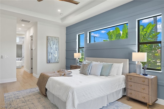 bedroom with ceiling fan, light wood-type flooring, and ensuite bath