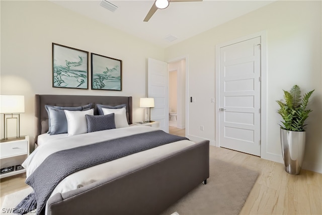 bedroom featuring ceiling fan, light hardwood / wood-style floors, and connected bathroom