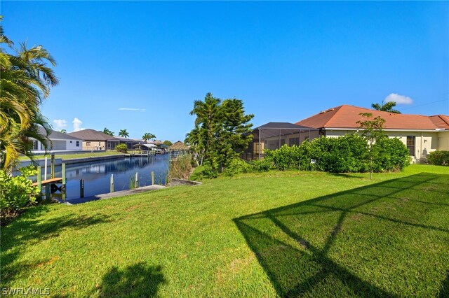 view of yard with a lanai, a dock, and a water view