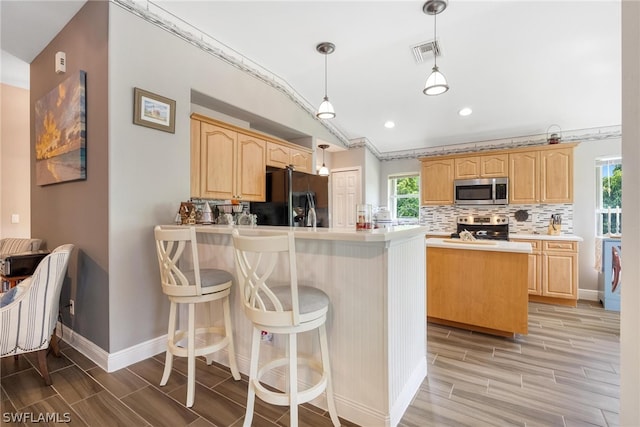 kitchen featuring plenty of natural light, a center island, light brown cabinetry, and stainless steel appliances