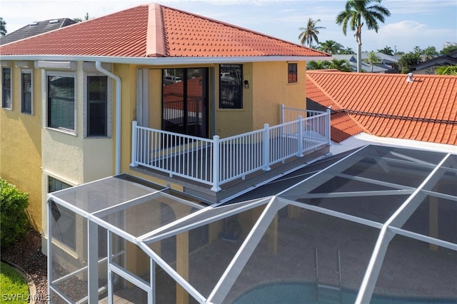 rear view of property with a balcony and glass enclosure