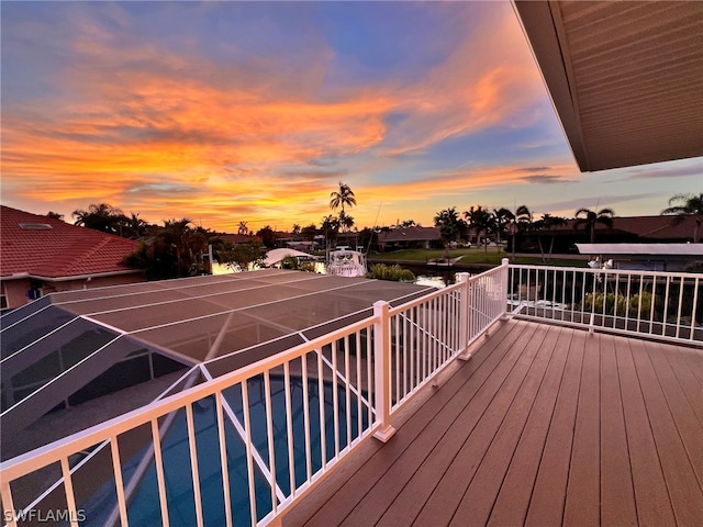 deck at dusk featuring glass enclosure