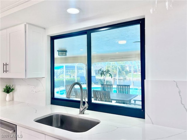 kitchen featuring light stone countertops, sink, and white cabinets