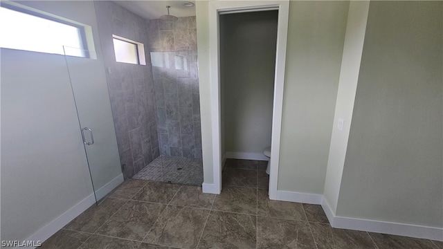 bathroom featuring tiled shower, toilet, and tile patterned floors