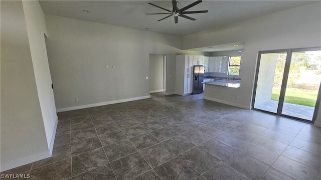 unfurnished living room with dark tile patterned floors and ceiling fan