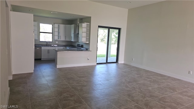 kitchen featuring kitchen peninsula, white cabinets, stainless steel dishwasher, electric range oven, and dark tile patterned flooring