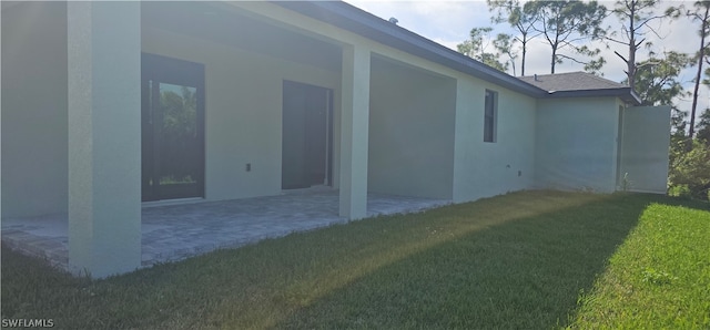 view of side of property featuring a patio area and a yard