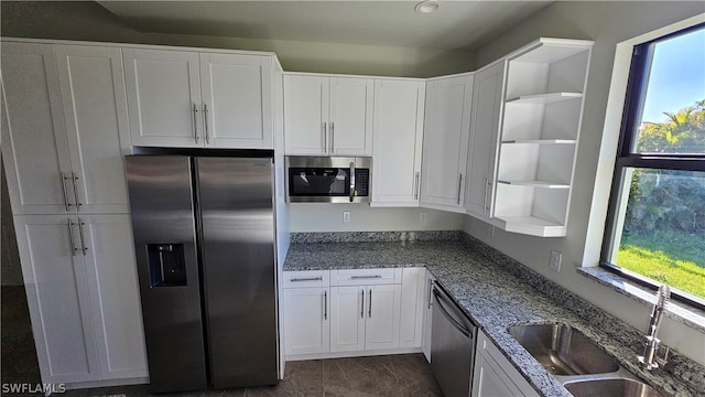 kitchen featuring sink, white cabinetry, dark stone counters, and stainless steel appliances