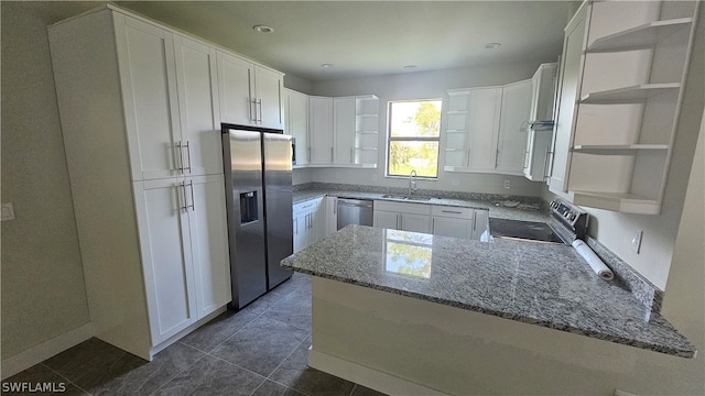 kitchen featuring kitchen peninsula, appliances with stainless steel finishes, dark stone countertops, and white cabinets