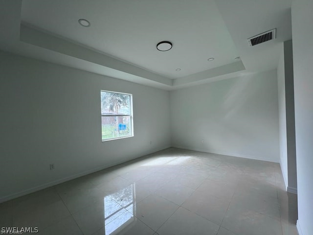 unfurnished room featuring tile patterned floors and a tray ceiling