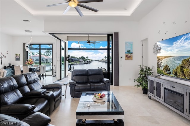 living room with ceiling fan and a tray ceiling