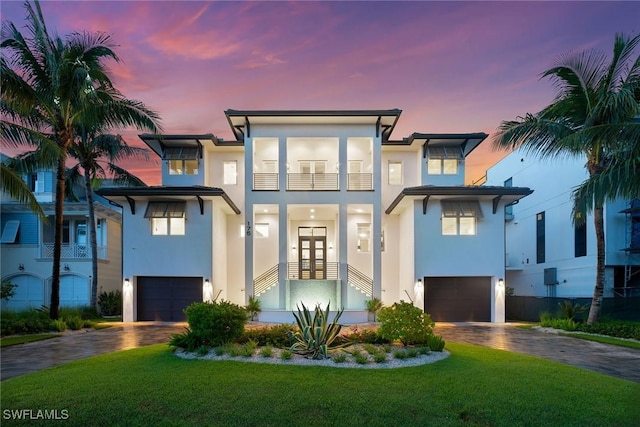 view of front of property with a lawn, french doors, a balcony, and a garage