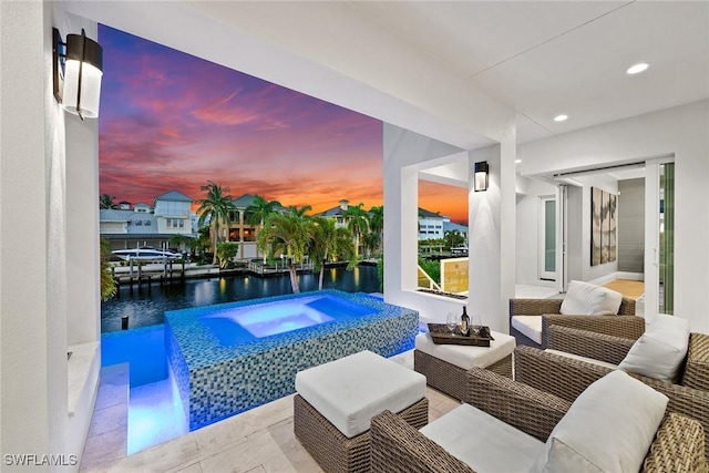 pool at dusk featuring a water view and an in ground hot tub