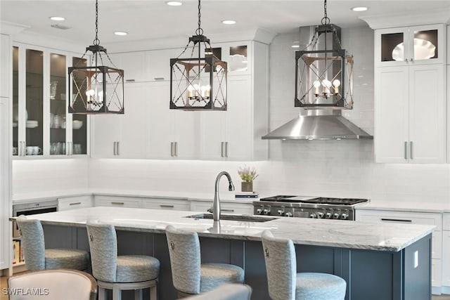 kitchen featuring pendant lighting, an island with sink, white cabinetry, and sink