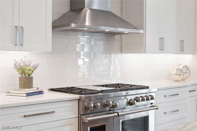 175 Conners Ave, Naples, FL 34108 - kitchen featuring wall chimney range hood, range with two ovens, tasteful backsplash, white cabinetry, and light stone counters