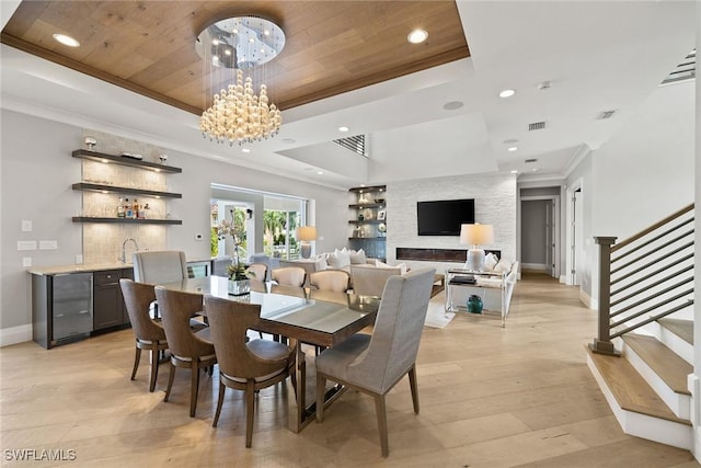 dining room featuring wooden ceiling, an inviting chandelier, light wood-type flooring, a tray ceiling, and ornamental molding