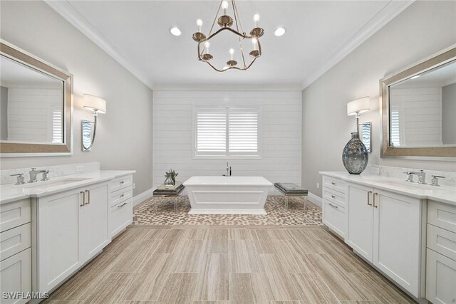 175 Conners Ave, Naples, FL 34108 - bathroom featuring a soaking tub, two vanities, a chandelier, baseboards, and crown molding