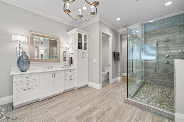 bathroom featuring vanity, crown molding, toilet, a shower with shower door, and a chandelier