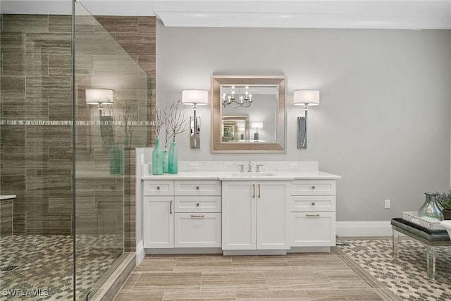 bathroom featuring a notable chandelier, vanity, a shower with door, and ornamental molding