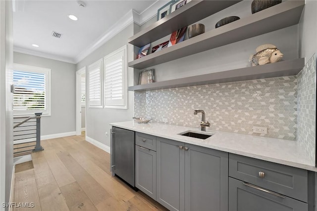 kitchen with gray cabinetry, crown molding, sink, light hardwood / wood-style flooring, and decorative backsplash