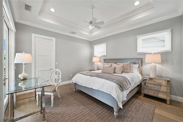 bedroom with dark hardwood / wood-style floors, a raised ceiling, ceiling fan, and crown molding