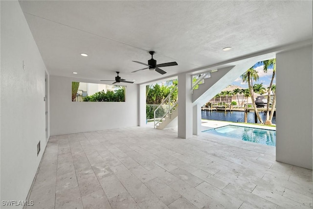 view of pool with ceiling fan, a patio area, and a water view