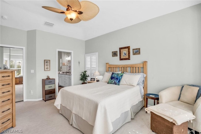 bedroom with ceiling fan, connected bathroom, and light colored carpet